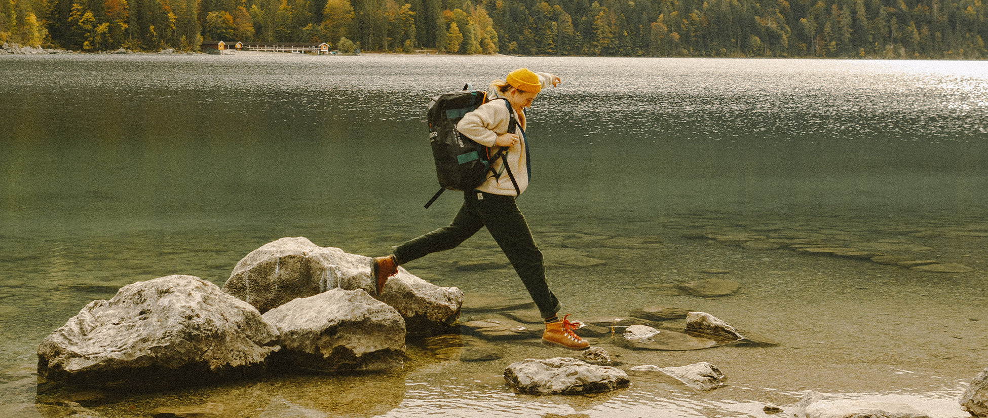 A person lakeside, jumping from a rock