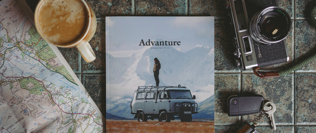 Advanture mag on a table, with camera, coffee and map