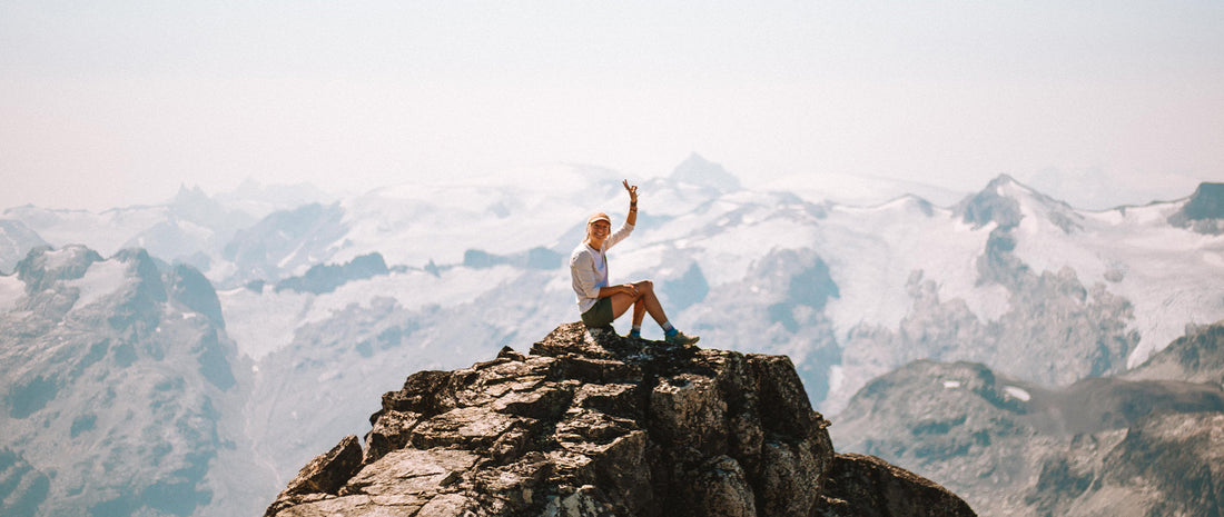 A person sits atop a mountain peak